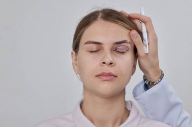 Blepharoplasty of a woman marking on her face before plastic surgery to change the eye area in a medical clinic clipart