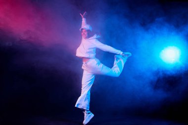 Açık renk elbiseli bir kız, dumanlı bir arka planda dans ediyor, modern dans.