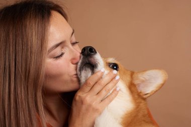 Kız Galli bir Corgi köpeğinin burnunu öpüyor, hayvan sevgisi konsepti.