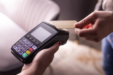 NFC kredi kartı ödemesi. NFC teknolojisiyle kredi kartıyla ödeme yapan bir kadın. Kablosuz para transferi. Kart makinesi erkek eliyle güneş ışığı arkaplanında