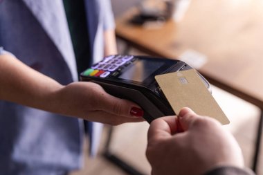 NFC kredi kartı ödemesi. NFC teknolojisiyle kredi kartıyla ödeme yapan bir kadın. Kablosuz para transferi. Kart makinesi erkek eliyle güneş ışığı arkaplanında