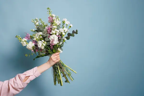 female florist makes a bouquet in a flower shop, spring bouquet