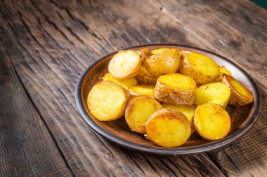 Koyu ahşap arka planda kızarmış patates dilimleri.