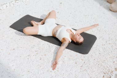 Yoga dışarıda geriniyor. Beyaz arka planda yoga yapan kilolu kadının yan görünüşü, vücut bakımı kavramı