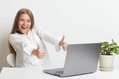 Bilgisayarlı mutlu kız ofiste başarılı bir işe, başarılı bir işe, çevrimiçi kazanana, başarılı bir karara seviniyor