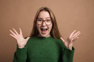 Bu tarif, gözlüklü ve yeşil kazaklı genç bir kadını tasvir ediyor. Yüzünde şaşkınlık ifadesi var.