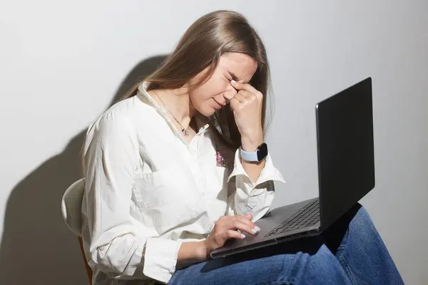 stock image tired girl at the table with a laptop after online classes