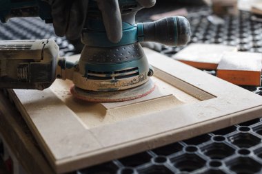 Erkek bir marangoz, mobilya fabrikasında zımpara makinesiyle ahşap mobilya cephesi, ahşap işleme konsepti.