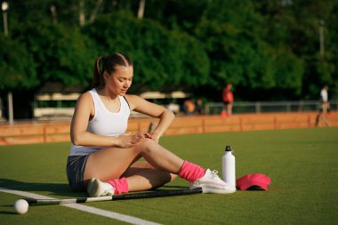 Kız hokey oyuncusu güneşli bir günde çim hokeyi oynuyor, hokey oyuncusu bir çim hokeyi oyununda sakatlandı, spor sakatlıkları