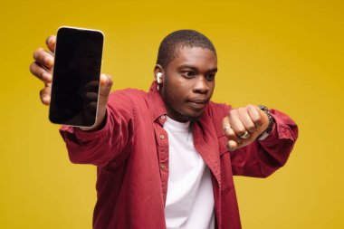 Mobil reklam. Mavi arka planda beyaz ekranlı cep telefonunu gösteren aşırı mutlu siyahi bir adam. Uygulama ya da web sitesi için bir model. Cep telefonu görüntüleme şablonu