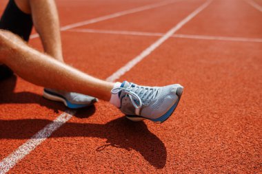 Koşmadan önce pistte oturan bir sporcu, Olimpiyat Oyunları 'nın başlamasına hazırlanıyor.