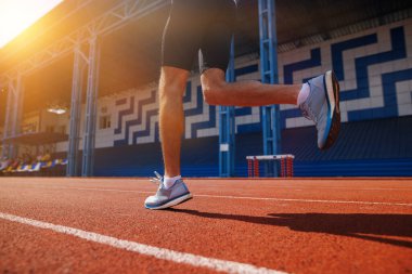 Stadyumdaki pistte koşan bir atlet, gün doğumunda çekilmiş, azim ve zindelik gösterisi yapıyor..