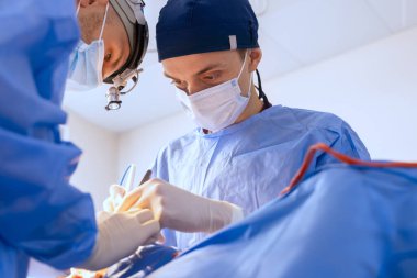 Erkek cerrahlar ameliyathanede, estetik cerrahlar ameliyathanede ameliyat yapıyor.