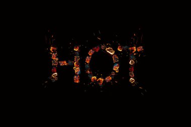 Karanlık arka planda sıcak kelimesi yanan kömürlerden yayılıyor. Yanan indirimler kavramı.