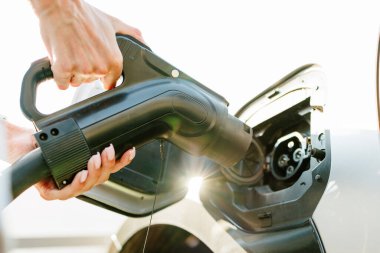 Bir kız elektrikli arabasını şarj istasyonunda, çevre dostu enerji kaynaklarında, yeşil enerji konseptinde, güneş enerjisinde şarj eder.