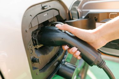 a girl charges her electric car at a charging station, Environmentally friendly energy sources, green energy concept, solar energy clipart