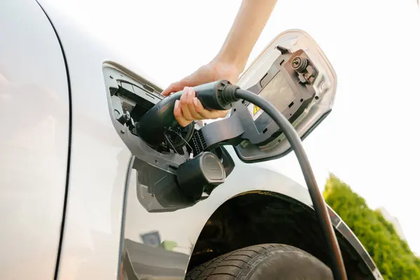 stock image a girl charges her electric car at a charging station, Environmentally friendly energy sources, green energy concept, solar energy