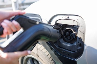 a girl charges her electric car at a charging station, Environmentally friendly energy sources, green energy concept, solar energy clipart