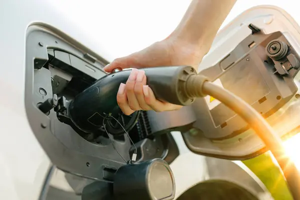 stock image a girl charges her electric car at a charging station, Environmentally friendly energy sources, green energy concept, solar energy