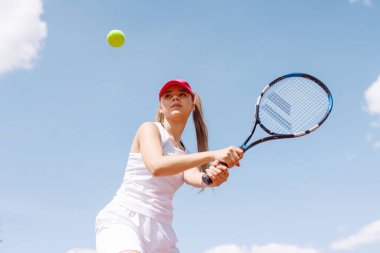 Genç kadın tenis oynuyor, tenis oynuyor.