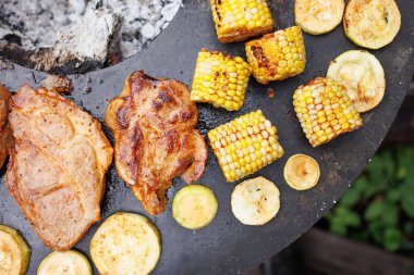 Izgarada balık, tavuk, mısır ve kabak dahil olmak üzere çeşitli ızgara et ve sebzeler açık hava bahçesinde sergileniyor..