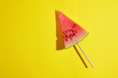 Sarı zemin üzerinde üçgen karpuz parçası, yaz konsepti.