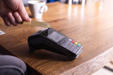 NFC kredi kartı ödemesi. NFC teknolojisiyle kredi kartıyla ödeme yapan bir kadın. Kablosuz para transferi. Kart makinesi erkek eliyle güneş ışığı arkaplanında