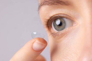 Yumuşak kontakt lens takan kız gözünün yanında kontak lens tutuyor, makro fotoğraf çekiyor.,