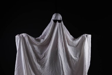 Hayalet kostümlü biri karanlık arka planda mesaj için yeri olan bir şeyi işaret ediyor. Cadılar Bayramı