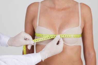Doktor bir mezura kullanarak hastanın göğüs ölçüsünü ölçer. Göğüs boyutunu arttırma konsepti