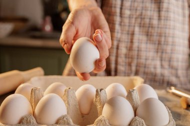 Mutfak arka planında kırık yumurtayla çırpılmış yumurta için kalp şeklinde kızartma tavası, yumurtalı karton kutu ve yerde birkaç kırık yumurta kabuğu var..
