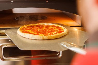 Pizza kabuğu kullanılarak pizza fırınından yeni çıkarılmış bir pizza..