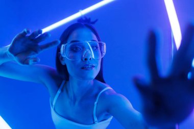 şeffaf gözlüklü sanal kız gelecekteki bir mekanda, neon ışıkları, siber uzay ile çevrili.