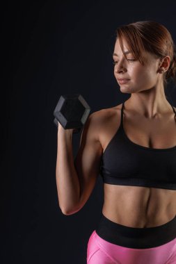 Sportif kız siyah arka plan, spor konsepti, sağlıklı ve güzel vücut üzerinde dambıllarla egzersiz yapıyor.