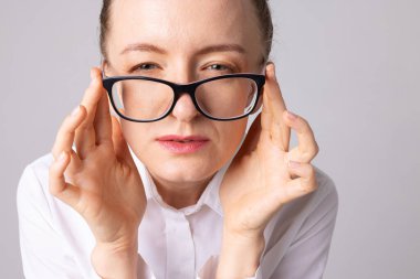 Görme yeteneği zayıf olan bir kadın görüşüne odaklanmak için gözlerini kısar. Optik konsepti ve gözlük seçimi.