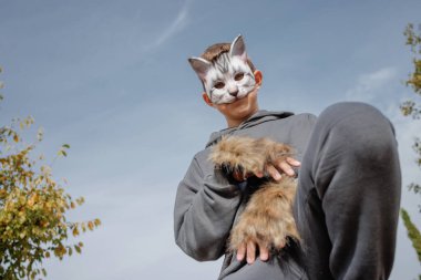 Kedi maskeli kuadrobik genci parkta dört ayak üstünde oturur, kuadrobika alt kültürü hayvan eylemlerinin taklidi