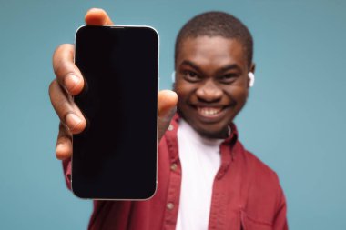 Mobil reklam. Mavi arka planda beyaz ekranlı cep telefonunu gösteren aşırı mutlu siyahi bir adam. Uygulama ya da web sitesi için bir model. Cep telefonu görüntüleme şablonu