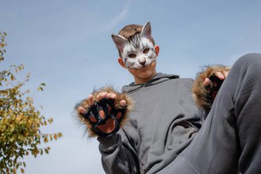 Kedi maskeli ve eldivenli genç Quadrobic yapıyor. Kuadrobik maskeli agresif genç kedi gibi zıplıyor.