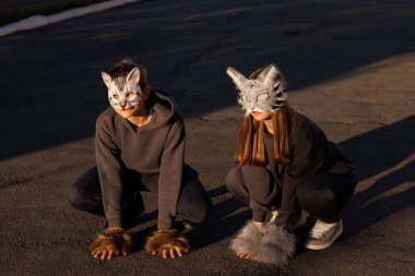 Kedi maskeli kız ve oğlan şehirde kuadrobik yapıyor, hayvan davranışları simülasyonu, kuadrobik sporu.