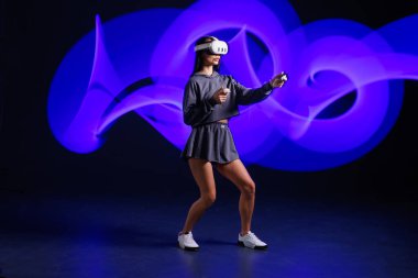 VR, AR, MR, XR Gelecek Teknolojileri. Neon. VR gözlüklü genç kız spor yapıyor ve oyun oynuyor. Modern cihazlar ve teknolojiler kavramı