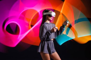 VR, AR, MR, XR Gelecek Teknolojileri. Neon. VR gözlüklü genç kız spor yapıyor ve oyun oynuyor. Modern cihazlar ve teknolojiler kavramı