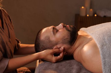 Masöz romantik, sıcak bir atmosferde kulak memelerine masaj yapar. Etrafı mumlarla çevrili, rahatlatıcı bir masaj yapar.