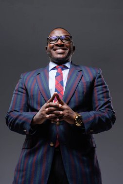 Yakışıklı, Afro-Amerikan iş adamı takım elbiseli ve kravatlı, temiz gri arka planda, aşağıdan çekilmiş, başlangıç konsepti