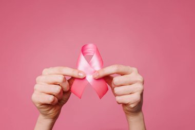 Pembe arka planda pembe kurdele tutan kadın, yakın plan. Göğüs kanseri farkındalığı konsepti,