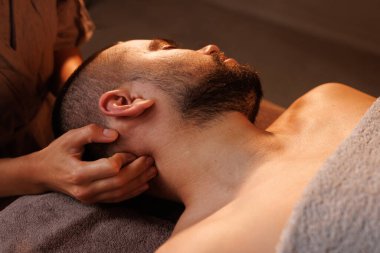 Adam spa salonunda profesyonel boyun masajı yaptırıyor.