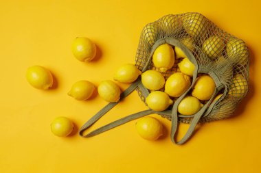 Üst manzara ağları taze limonlarla dolu parlak sarı arka plan, taze meyveler.