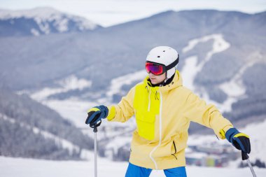Bir kayakçı maskesi ve kask karla kaplı dağlar ve mavi gökyüzü bir arka plan karşı kapalı bir yüz ile yakın çekim portre,