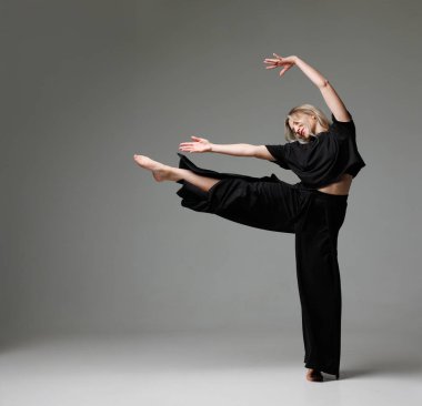 Siyah kıyafetli dansçı, dinamik pozlar veriyor. Kolları ve bacakları koyu arkaplanda ileri uzanıyor. konsept modern dans