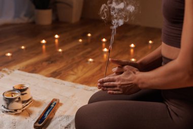 Yanan tütsü ve mumlarla meditasyon yapan, sakin ve huzurlu bir atmosfer yaratan bir kadının yakın çekimi..