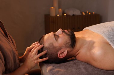 Rahatlamış bir adam, sakin bir spa ortamında, sakin bir ortam ve huzurlu bir atmosferde kafa masajı yapıyor..